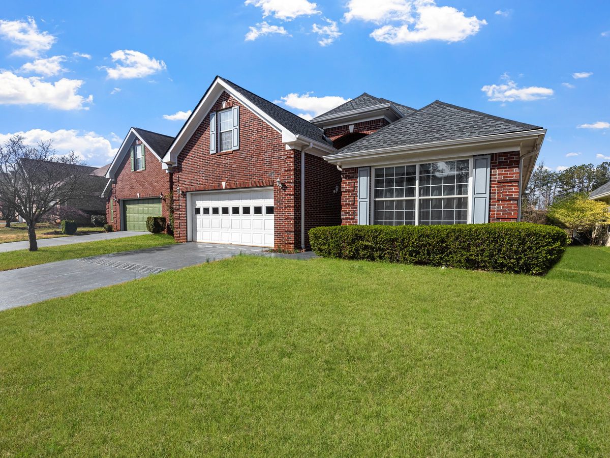 A red brick house with a finished roof and a clean, trimmed lawn