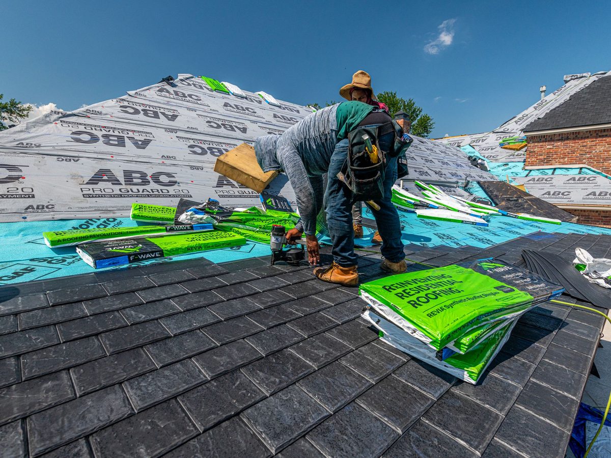 Crew installing a synthetic slate roof on a brick home
