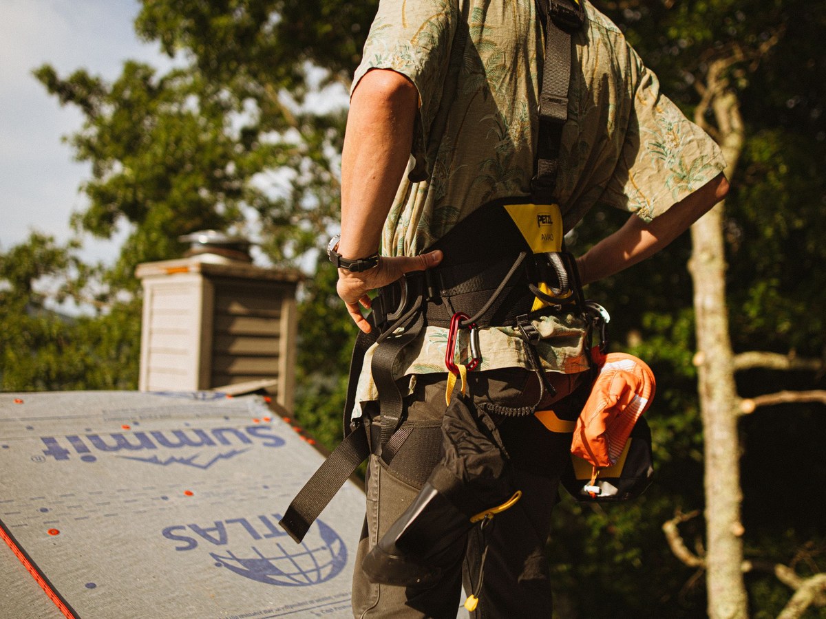 A roofer working in a safety harness high on a steep slope